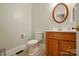 Well-lit half bathroom featuring a wood vanity with a round mirror and classic fixtures at 102 Rosewood Ln, Locust, NC 28097