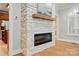 Close-up of a modern fireplace with a stone surround, a wooden mantel, and adjacent views of the kitchen and living area at 102 Rosewood Ln, Locust, NC 28097