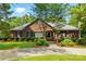 Beautiful red brick home with a well-kept lawn, mature trees, and a spacious driveway leading to a welcoming entrance at 102 Rosewood Ln, Locust, NC 28097