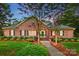 Charming brick home featuring a manicured front lawn, mature trees, and inviting entrance, perfect for a serene suburban lifestyle at 102 Rosewood Ln, Locust, NC 28097