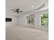 An expansive bedroom with a dark ceiling fan, a TV, and lots of windows bringing views of the outside at 10508 Kristens Mare Dr, Charlotte, NC 28277