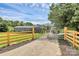Gated driveway entrance with a wood fence and a decorative metal gate on a sunny day at 117 Autumn Woods Dr, Kings Mountain, NC 28086