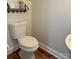 Neat half bathroom with a wall-mounted sink, toilet, and a decorative shelf overhead at 12904 Windy Lea Ln, Huntersville, NC 28078