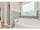 Bright bathroom featuring a white soaking tub, mosaic tiles and separate walk-in shower at 13407 Morgan Lee Ave, Charlotte, NC 28213