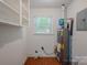 Bright laundry room featuring terra cotta tile floors, utility shelving, and water heater at 1401 Hillwood Ct, Charlotte, NC 28210