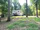A beautiful backyard with trees surrounding a two-story white home with a wood deck at 14027 Hackamore Dr, Matthews, NC 28105