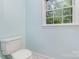 Bright bathroom with a toilet and a window overlooking the trees at 14027 Hackamore Dr, Matthews, NC 28105