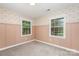 Charming bedroom featuring warm wallpaper, fresh neutral paint, and a bright window with a treed view at 14027 Hackamore Dr, Matthews, NC 28105