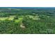 Aerial view showcasing a home nestled among lush trees and greenery, emphasizing its private, natural setting at 15025 Barbee Rd, Stanfield, NC 28163