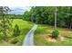 Gravel driveway leading through a lush green lawn and mature trees at 15025 Barbee Rd, Stanfield, NC 28163