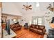 Spacious living room featuring hardwood floors, leather sofas, a ceiling fan, and seamless access to the kitchen and dining areas at 15025 Barbee Rd, Stanfield, NC 28163