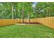 Lush backyard with green grass, tall trees, and a wood privacy fence at 1834 Arnold Dr, Charlotte, NC 28205