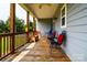 Covered porch with wood floors, wooden railings, and multiple seating options at 1858 Brevard Place Rd, Iron Station, NC 28080