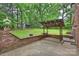 Backyard featuring a brick patio, a wooden pergola with lights, and a grassy area with surrounding trees at 2301 Seth Thomas Rd, Charlotte, NC 28210