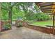 Backyard featuring a brick patio, a wooden pergola with lights, and a grassy area surrounded by trees at 2301 Seth Thomas Rd, Charlotte, NC 28210