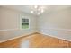 Bright bedroom features hardwood floors, a modern light fixture, and a window view to the outdoors at 2301 Seth Thomas Rd, Charlotte, NC 28210