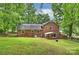 Rear exterior of the brick home features a covered patio, lush yard, and peaceful setting at 2301 Seth Thomas Rd, Charlotte, NC 28210