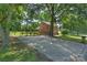 Side view of brick home with a long driveway in a lush, private setting with mature trees at 2301 Seth Thomas Rd, Charlotte, NC 28210