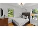 Cozy bedroom with hardwood floors, featuring large windows, stylish headboard, matching nightstands and modern decor at 2424 Cumberland Ave, Charlotte, NC 28203