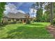 Expansive backyard with a well-maintained lawn, mature trees, and charming brick detailing at 3032 Kings Manor Dr, Matthews, NC 28104