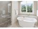 This bathroom offers a shower with glass enclosure and a stand-alone tub near a large window at 3032 Kings Manor Dr, Matthews, NC 28104