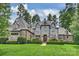 Stunning stone-clad home featuring a manicured lawn and lush, mature landscaping at 3032 Kings Manor Dr, Matthews, NC 28104