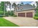 Spacious two-car garage with wooden doors and a wide driveway, set in a beautiful home exterior at 3032 Kings Manor Dr, Matthews, NC 28104