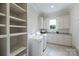 This laundry room features custom shelves, a sink, and a front load washer and dryer at 3032 Kings Manor Dr, Matthews, NC 28104