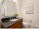 This powder room features a wood vanity with granite countertop, a framed mirror and a toilet at 3032 Kings Manor Dr, Matthews, NC 28104