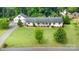 Aerial view of a well-maintained home with a lush lawn, mature trees, and a charming front porch at 309 Ogden Dr, Gastonia, NC 28056
