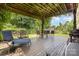 Covered back porch with seating area overlooking the expansive lawn and lush greenery, ideal for relaxation at 309 Ogden Dr, Gastonia, NC 28056