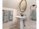 Cozy bathroom featuring a pedestal sink, oval mirror, and soft-colored towels at 309 Ogden Dr, Gastonia, NC 28056
