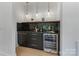Stylish bar area with a wine cooler, sleek black cabinets, and elegant marble backsplash at 309 Sain Rd, Statesville, NC 28625