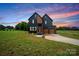 Striking two-story home with a modern design, well-manicured lawn, and a picturesque sunset backdrop at 309 Sain Rd, Statesville, NC 28625