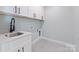 Bright laundry room featuring a sink, white cabinets, and modern fixtures at 3601 Woody Grove Ln, Charlotte, NC 28210