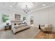 A spacious primary bedroom features a modern chandelier, tray ceiling and ensuite bathroom at 3601 Woody Grove Ln, Charlotte, NC 28210
