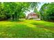 Lush backyard featuring expansive lawn, mature trees, deck, and two-story brick home at 4712 Amberside Dr, Rock Hill, SC 29732