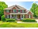 Beautiful two-story brick home with a manicured lawn, covered porch and dark shutters on a sunny day at 4712 Amberside Dr, Rock Hill, SC 29732