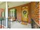 Inviting front porch featuring a wooden door with wreath, brick facade, and cozy seating area at 4712 Amberside Dr, Rock Hill, SC 29732