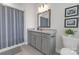 Traditional bathroom with gray vanity, decorative mirror, shower with curtain, and granite countertops at 5060 Harrowsmith Ln, Charlotte, NC 28204