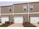 Exterior view of a townhouse with three white garage doors and brown siding at 512 Morrows Turnout Way, Pineville, NC 28134