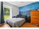 A cozy bedroom with a blue accent wall, a queen-sized bed, and natural light from the window at 6718 Pueblo Ln, Charlotte, NC 28227