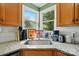 A well-lit kitchen sink featuring a granite countertop, wood cabinets, and a corner window with natural light at 6718 Pueblo Ln, Charlotte, NC 28227