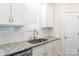 Close-up of kitchen with granite countertops, stainless steel sink, and white subway tile backsplash at 679 Cape Fear St, Fort Mill, SC 29715
