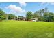 Expansive backyard with a large grassy area, mature trees, and outbuildings at 6900 Ridge Lane Rd, Charlotte, NC 28262