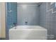 White bathtub with blue tile surround and updated fixtures at 6900 Ridge Lane Rd, Charlotte, NC 28262