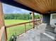Covered back porch with wooded ceiling, metal railing and view of the expansive backyard at 7133 Church Rd, Taylorsville, NC 28681