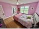 Bright bedroom with pink walls, plush bed, and large window offering a pleasant view at 7133 Church Rd, Taylorsville, NC 28681