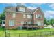A view of the rear brick exterior and fenced back yard with a deck at 8409 Olde Stonegate Ln, Mint Hill, NC 28227