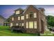 A view of the rear brick exterior and fenced back yard with a deck at dusk at 8409 Olde Stonegate Ln, Mint Hill, NC 28227